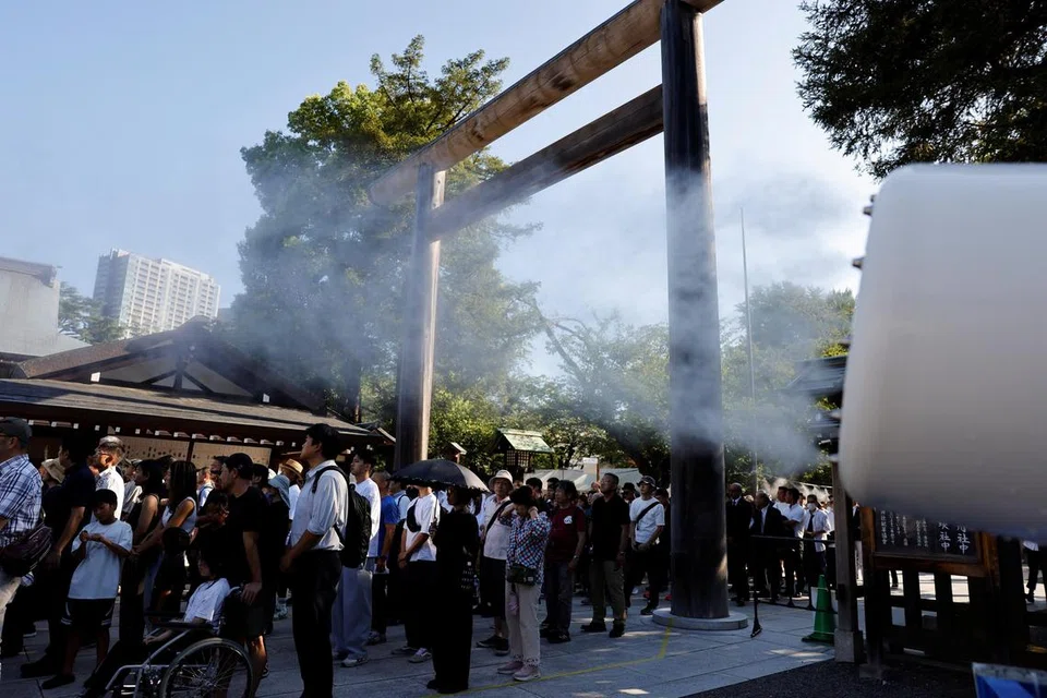 Orang ramai berdiri sambil disembur kabus air ketika menunggu untuk berdoa semasa lawatan mereka ke Kuil Yasukuni pada ulang tahun ke-80 penyerahan Jepun dalam Perang Dunia Kedua, di Tokyo, Jepun, 15 Ogos 2025.