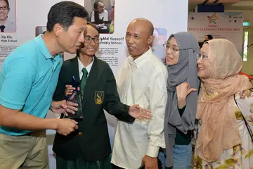TUNGGAK KEJAYAAN: Pemenang Anugerah S.T.A.R, Siti A'dlina Md Yussoff (dua dari kiri), memperkenalkan Encik Ong Ye Kung kepada (dari kanan) ibunya, Cik Hasnah Bakar; kakaknya, Cik Siti Amalina; dan bapanya, Encik Md Yussoff Hussain; yang menggalakkannya terlibat dalam kerja sukarela. - Foto ZAINAL YAHYA