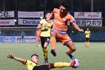 MEMPERTAHANKAN GAWANG: Fadli Khamis berjaya membendung kelincahan Kenya Takahashi (jersi jingga) dalam perlawanan yang berlangsung di stadium Jurong East kelmarin. - Foto ZAINAL YAHYA