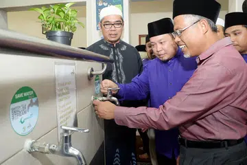 TUKAR PAIP UNTUK JIMAT AIR: Pengerusi Masjid Mujahidin, Encik Muhammad Khairul Jameel (tengah), menunjukkan cara bagaimana pihak masjid menjimatkan air di tempat mengambil wuduk kepada Encik Masagos (kanan) sambil disaksikan relawan masjid, Encik Mustafa Ismail (kiri). - Foto JOHARI RAHMAT