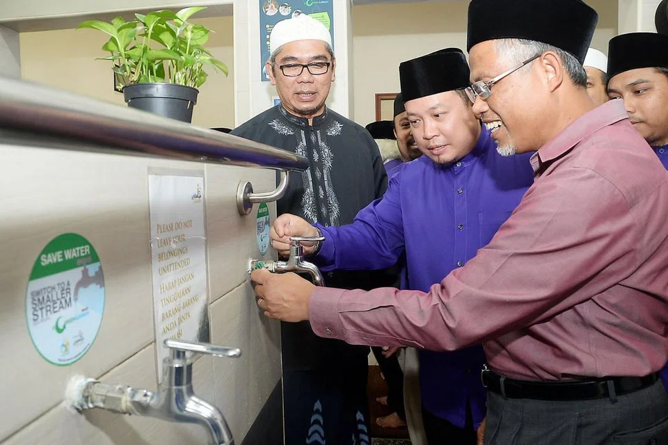 TUKAR PAIP UNTUK JIMAT AIR: Pengerusi Masjid Mujahidin, Encik Muhammad Khairul Jameel (tengah), menunjukkan cara bagaimana pihak masjid menjimatkan air di tempat mengambil wuduk kepada Encik Masagos (kanan) sambil disaksikan relawan masjid, Encik Mustafa Ismail (kiri). - Foto JOHARI RAHMAT