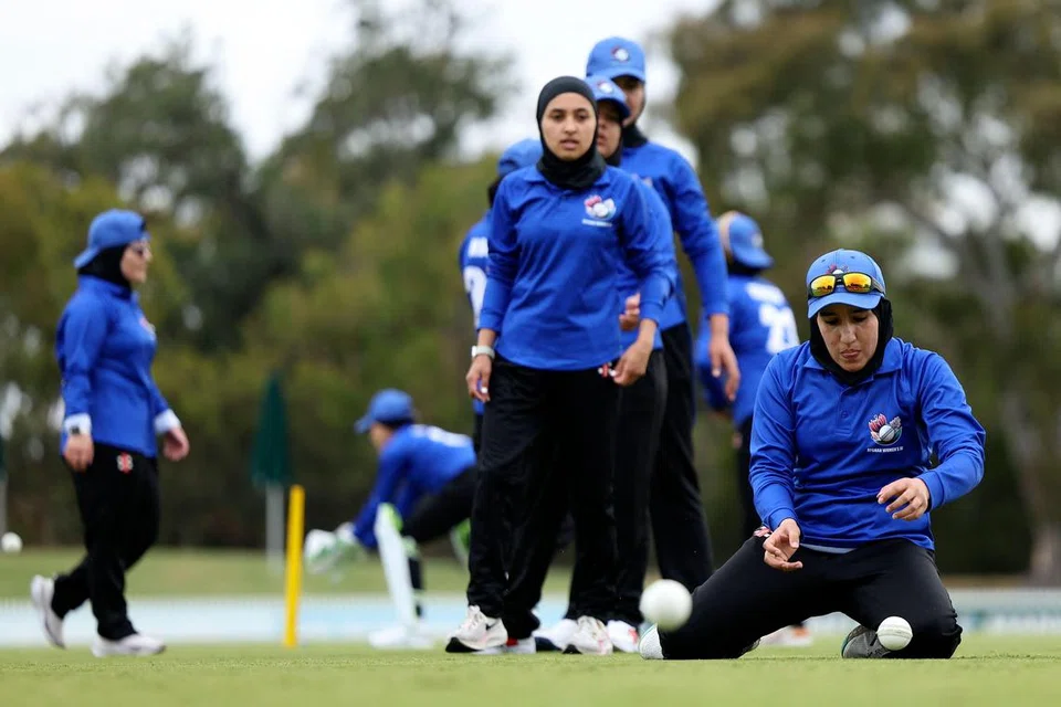 Firooza Amiri (depan, dua dari kanan) dan kapten pasukan, Nahida Sapan (kanan) yang membentuk sebahagian daripada pasukan kriket wanita Afghanistan, menjalani latihan memanaskan badan sebelum menentang pasukan Cricket Without Borders, di Melbourne, Australia, pada 30 Januari.