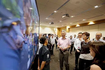 PERTEMUAN MESRA: Perdana Menteri, Encik Lee Hsien Loong kelihatan berbual dengan seorang anggota polis tambahan bersama-sama Menteri Tenaga Manusia, Cik Josephine Teo (tiga dari kanan), semasa mengunjungi pusat kerjaya Careers Connect Tenaga Kerja Singapura (WSG) semalam. - Foto LIANHE ZAOBAO