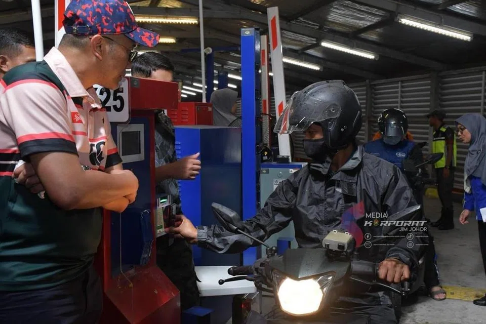 Pengguna motosikal warga Malaysia (kanan) mencuba penggunaan kod respons pantas (QR) untuk pelepasan Jabatan Imigresen di Kompleks Kastam, Imigresen dan Kuarantin (CIQ) di Kompleks Sultan Abu Bakar (KSAB) Johor Bahru yang bermula pada 1 Jun. Timbalan Ketua Setiausaha (Dasar dan Kawalan) Kementerian Dalam Negeri, Datuk Zamri Mat Zain (kiri), turun padang bagi meninjau pelaksanaan pembuktian konsep (POC) kod QR itu di KSAB.