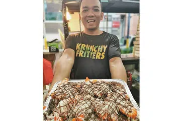 PERLU TELITI: Encik Muhammad Hafiz Abdul Rahman memastikan adunan tepung dibuat dengan teliti agar pisang goreng yang dihasilkan garing dan tahan lama. - Foto KRUNCHY FRITTERS