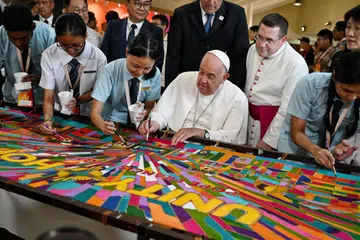 Paus (Pope) Francis (tengah) menyiapkan lukisan batik pada 13 September di Maktab Rendah Katolik (CJC) sebelum menghadiri sesi pertemuan bersama golongan muda. Batik tersebut memberi erti keharmonian kaum dan agama di Singapura setelah ia diusahakan bersama kakitangan dan pelajar CJC.