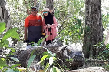HASRAT TERCAPAI: Walaupun rasa takut, penulis dan suami beranikan diri berfoto bersama naga komodo yang sedang berehat. - Foto ihsan HASNAH ABDULLAH