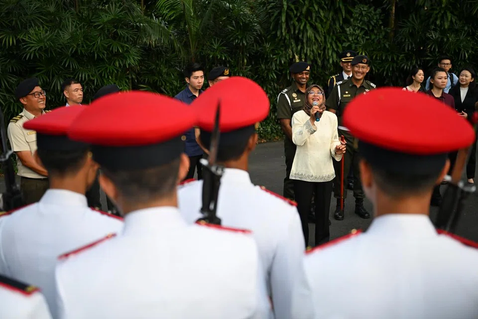 HARGAI KHIDMAT: Puan Halimah menyampaikan ucapan sewaktu menyaksikan istiadat pertukaran pengawal yang berlangsung di Istana pada Ahad. Upacara itu disaksikan ramai pejalan kaki (gambar atas).