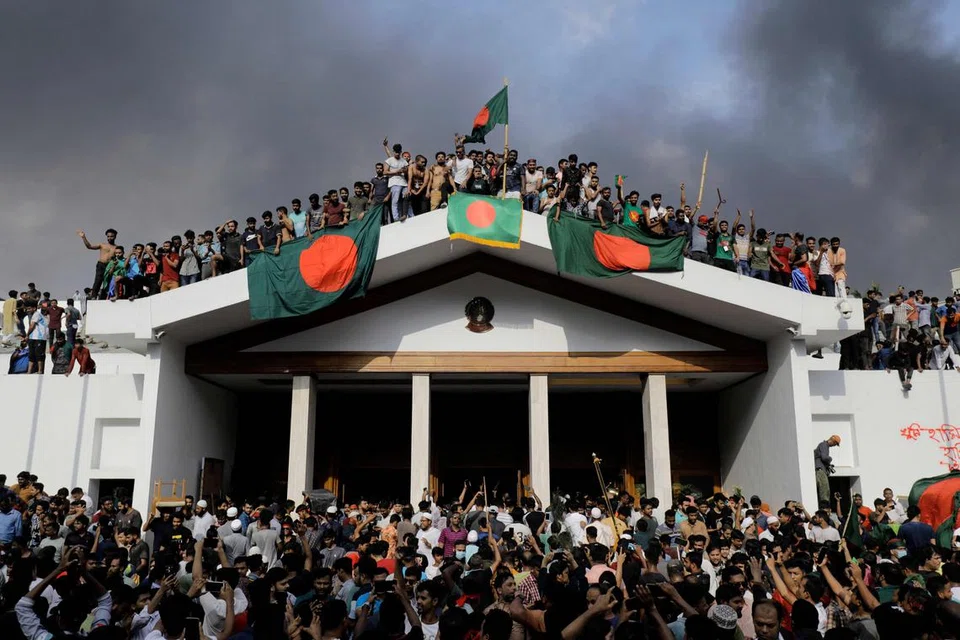 Penunjuk perasaan antipemerintah mengibarkan  bendera Bangladesh ketika mereka menyerbu istana Perdana Menteri Sheikh Hasina di Dhaka pada 5 Ogos 2024.