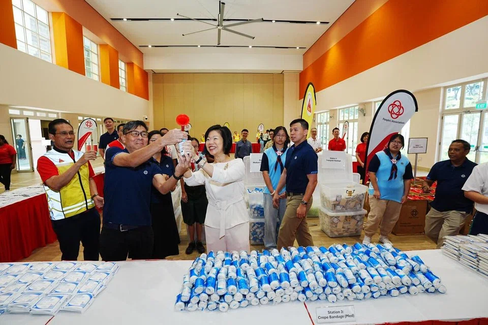 Tetamu terehormat, Menteri Negara Kanan (Ehwal Luar merangkap Ehwal Dalam Negeri), Cik Sim Ann (tengah) bersama 200 pandu puteri dan pengakap membekal 1,000 beg kecemasan untuk mencatatkan rekod dalam Buku Rekod Singapura. Beg kecemasan tersebut akan diagihkan kepada pusat PA C2E dan Pusat Operasi Krisis Kawasan (CCOC) di serata negara.