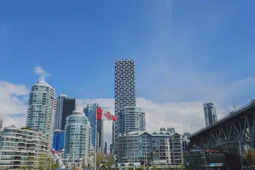 Panorama bandar raya di Granville Island, Vancouver yang menawan dengan bendera Canada berkibar megah di bawah langit biru yang cerah.