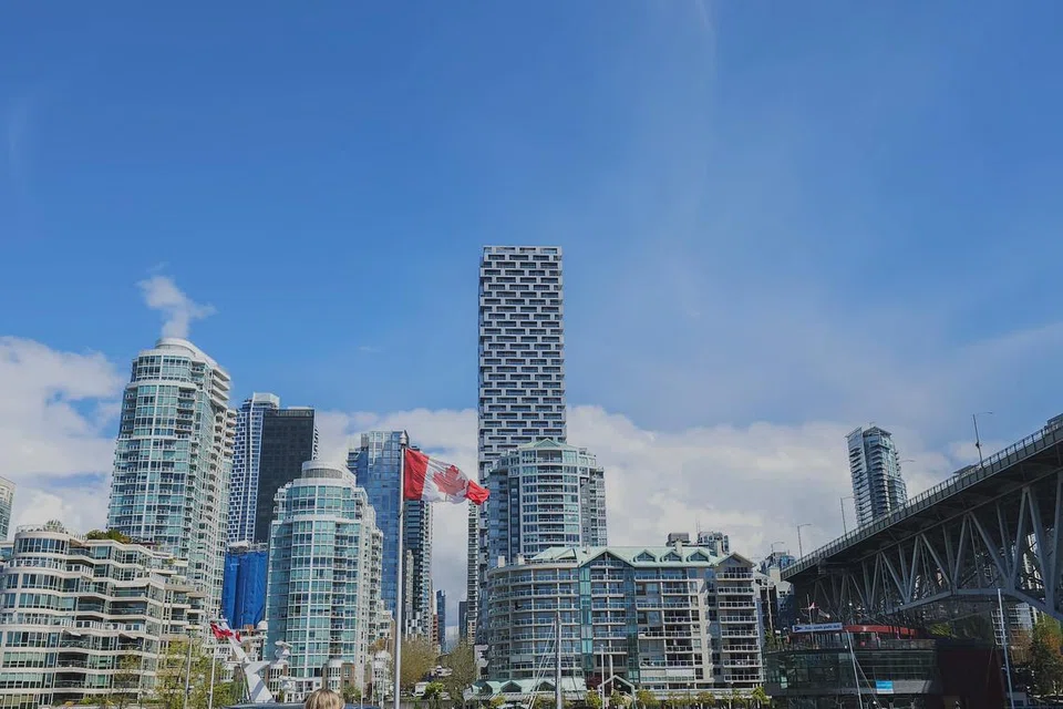 Panorama bandar raya di Granville Island, Vancouver yang menawan dengan bendera Canada berkibar megah di bawah langit biru yang cerah.