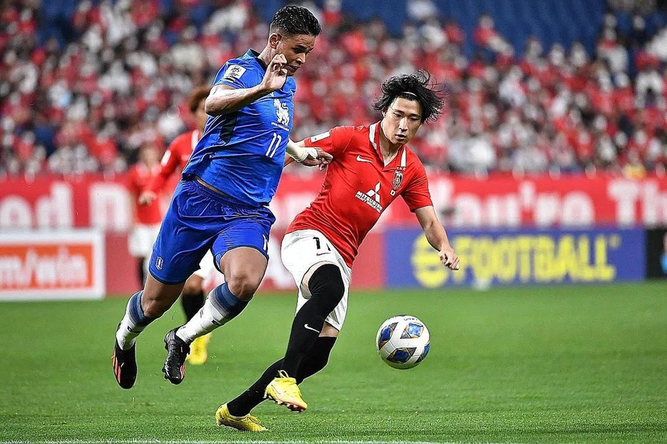 BERAKSI: Irfan Fandi (kiri) bersaing untuk berebut bola dengan pemain Urawa, Yusuke Matsuo sewaktu kejuaraan Liga Juara-Juara AFC. - Foto AFP