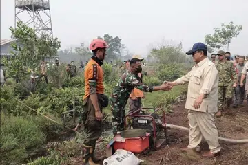 Presiden Indonesia, Encik Prabowo Subianto (kanan), bersalaman dengan seorang anggota pasukan yang terlibat dalam operasi memadam kebakaran hutan dan tanah ketika meninjau kawasan terjejas di Kalimantan Barat pada 22 Ogos 2026. Lawatan itu dilakukan ketika kebakaran terus melanda beberapa wilayah di Kalimantan, mendorong pemerintah mengerahkan tiga batalion tambahan tentera membabitkan sekitar 1,500 anggota, enam helikopter berkapasiti besar bagi operasi pengeboman air serta menambah operasi pengubahsuaian cuaca, pam dan kerja penggerudian sumber air.