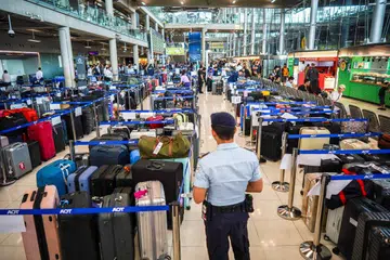 Seorang anggota keselamatan lapangan terbang berdiri bersebelahan timbunan bagasi penumpang Thai Airways di Lapangan Terbang Antarabangsa Suvarnabhumi, Bangkok, pada 29 September 2026. Hujan lebat dan banjir menjejas operasi darat syarikat penerbangan itu sehingga menyebabkan ribuan bagasi terkandas