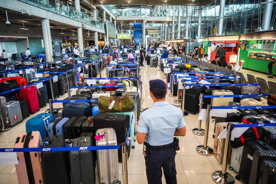 Seorang anggota keselamatan lapangan terbang berdiri bersebelahan timbunan bagasi penumpang Thai Airways di Lapangan Terbang Antarabangsa Suvarnabhumi, Bangkok, pada 29 September 2026. Hujan lebat dan banjir menjejas operasi darat syarikat penerbangan itu sehingga menyebabkan ribuan bagasi terkandas