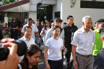 Mantan penjawat awam kanan, Cik Jasmin Lau (tengah), dan tokoh veteran Parti Tindakan Rakyat (PAP), Encik Victor Lye (kiri), dilihat menyertai lawatan turun padang di GRC Ang Mo Kio bersama Menteri Kanan, Encik Lee Hsien Loong (kanan), pada 13 April.