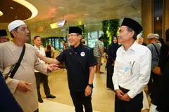 Ketua Delegasi Haji Singapura 2024 dan Menteri di Pejabat Perdana Menteri, Dr Mohamad Maliki Osman (tengah), beramah mesra dengan anggota keluarga yang sedang menanti kepulangan jemaah haji, sambil diiringi Presiden Majlis Ugama Islam Singapura (Muis), Encik Saat Abdul Rahman (kanan).