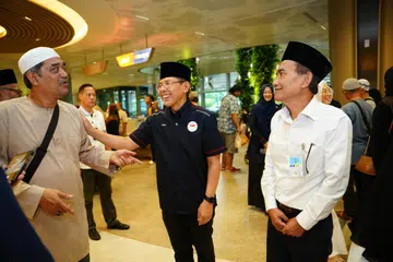 Ketua Delegasi Haji Singapura 2024 dan Menteri di Pejabat Perdana Menteri, Dr Mohamad Maliki Osman (tengah), beramah mesra dengan anggota keluarga yang sedang menanti kepulangan jemaah haji, sambil diiringi Presiden Majlis Ugama Islam Singapura (Muis), Encik Saat Abdul Rahman (kanan).