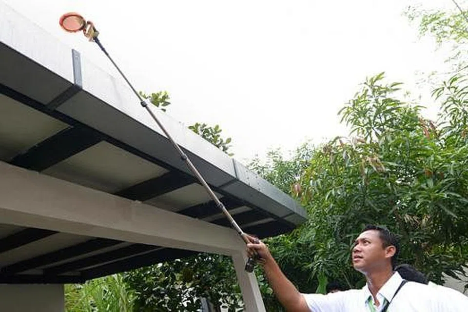 PEMERIKSAAN KETAT: Seorang pegawai Agensi Sekitaran Kebangsaan (NEA) memeriksa bumbung sebuah rumah bagi memastikan tiada pembiakan nyamuk Aedes di kawasan ada takungan air. - Foto fail