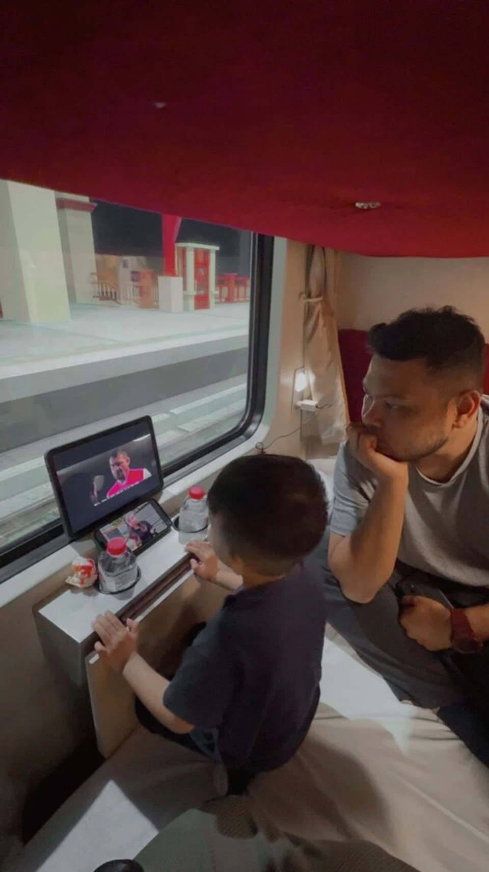 Encik Khairul Rasul Hamidi bersama anaknya, Luth Rifqi Khairul Rasul menonton iPad bersama di dalam kereta api.