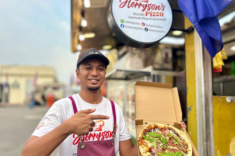 Encik Muhammad Hazrin Herryson bersama salah satu menu paling laris di gerainya-roasted duck pizza. Beliau berkata kesan sampingan yang perlu diperhatikan ialah kemungkinan nilai hartanah dan kadar sewa premis meningkat.