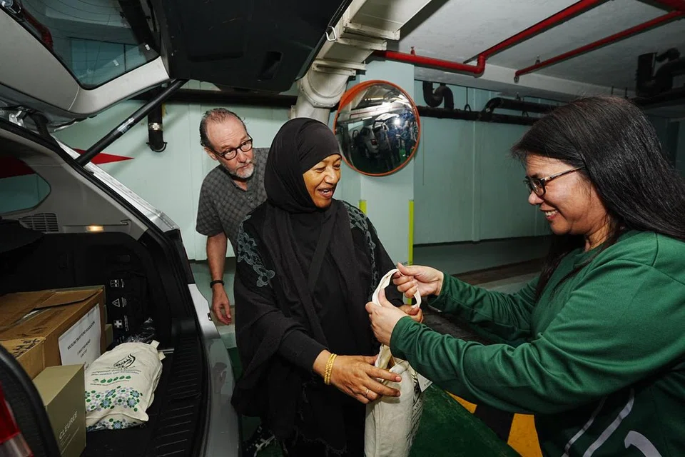 Relawan Cik Bina Rahman (tengah) mengambil pek bantuan untuk diagihkan di kawasan barat.