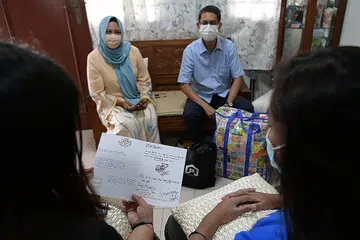 JALIN SEMULA HUBUNGAN KELUARGA: Dr Faishal (tiga dari kiri) dan Cik Haslinda (dua dari kiri) memerhati Lisa (paling kiri) dan Lina (paling kanan) membaca kad Hari Raya yang ditulis ibu mereka, seorang banduan selama 12 tahun. - Foto BH oleh NG SOR LUAN