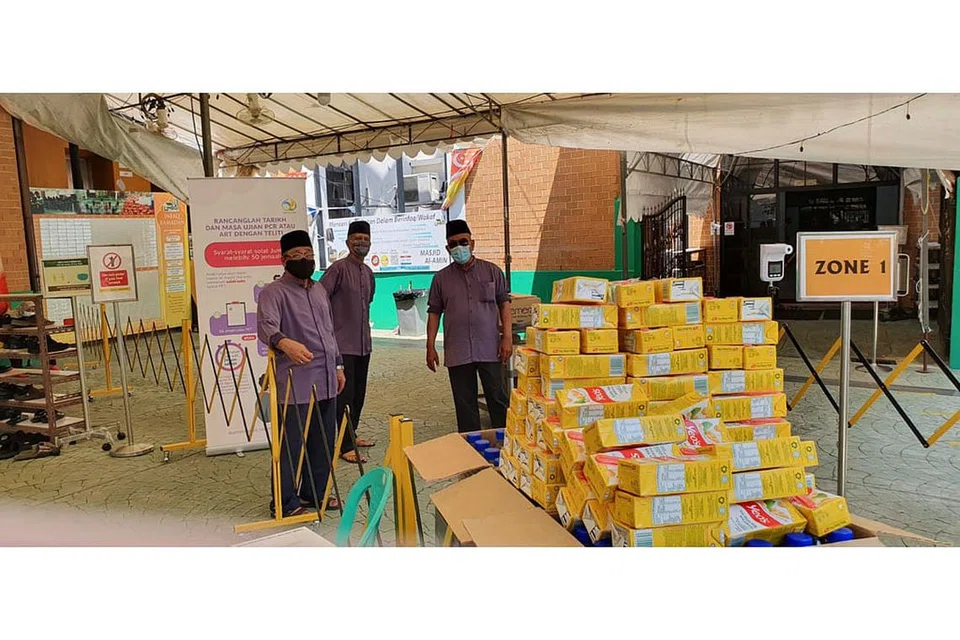 TERUS DEKATI MASYARAKAT: Petugas dan relawan Masjid Al-Amin (dari kiri), Encik Mohamed Kassim Abdul Hamid, Encik Johari Mohamed Sainee dan Encik Ali Ahmad sedang mempersiap laluan masuk dan keluar masjid di zon-zon yang tersedia beserta minuman air kotak dan mineral untuk diambil para jemaah sewaktu pulang dari solat Jumaat. - Foto MASJID AL-AMIN.