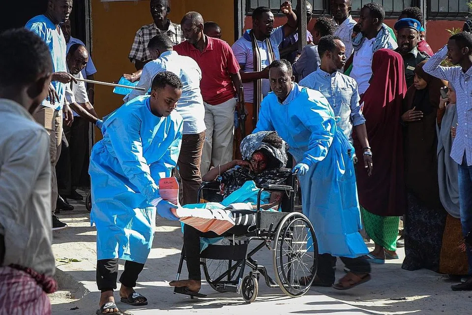 MUJUR SELAMAT: Seorang wanita yang cedera ditolak dengan kerusi roda setibanya di Hospital Madina di Mogadishu kelmarin. - Foto AFP