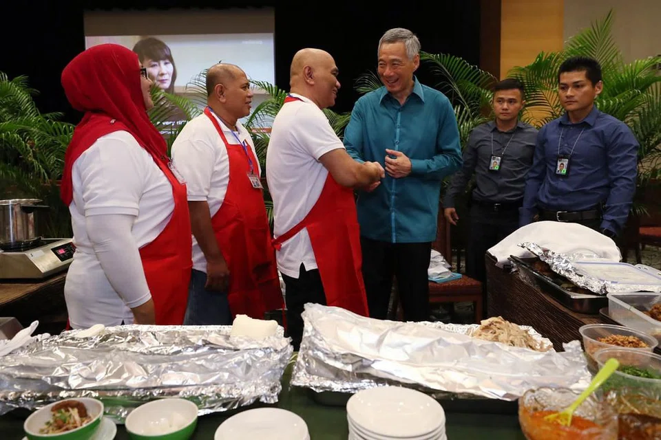 PROMOSI BUDAYA PENJAJA: Encik Lee berjabat tangan dan berinteraksi dengan pemilik Hani Food Stall di Clementi, Encik Md Zainal Onan, yang menghidangkan mi soto kepada para tetamu Rapat Hari Kebangsaan kelmarin. - Foto BH oleh GAVIN FOO