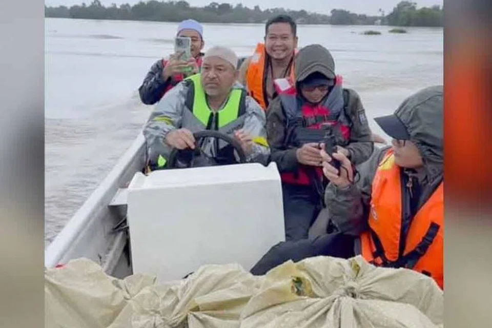 Menteri Besar Kelantan, Datuk Mohd Nassuruddin Daud (depan kiri), keluar meredah banjir bagi mengagihkan bantuan kepada penduduk terjejas di daerah Pasir Mas, Kelantan.