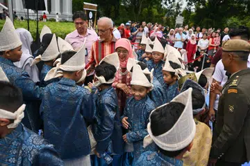 SAMBUTAN MESRA: Presiden Halimah Yacob (tengah) dan suaminya, Encik Mohammed Abdullah Alhabshee (di belakang Puan Halimah) beramah mesra dengan murid-murid dari Madrasah Irsyad Zuhri Al-Islamiah yang membuat persembahan dikir barat. 