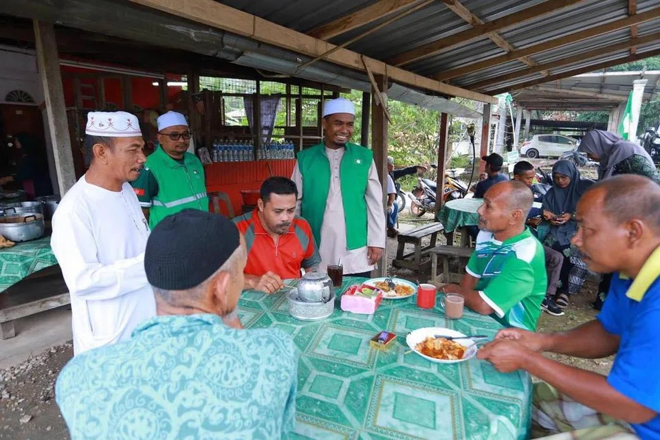Calon Perikatan Nasional, Encik Mohd Rizwadi Ismail (berdiri, kanan) menyantuni pengundi sempena kempen pilihan raya kecil Dewan Undangan Negeri Nenggiri, di Gua Musang, Kelantan.