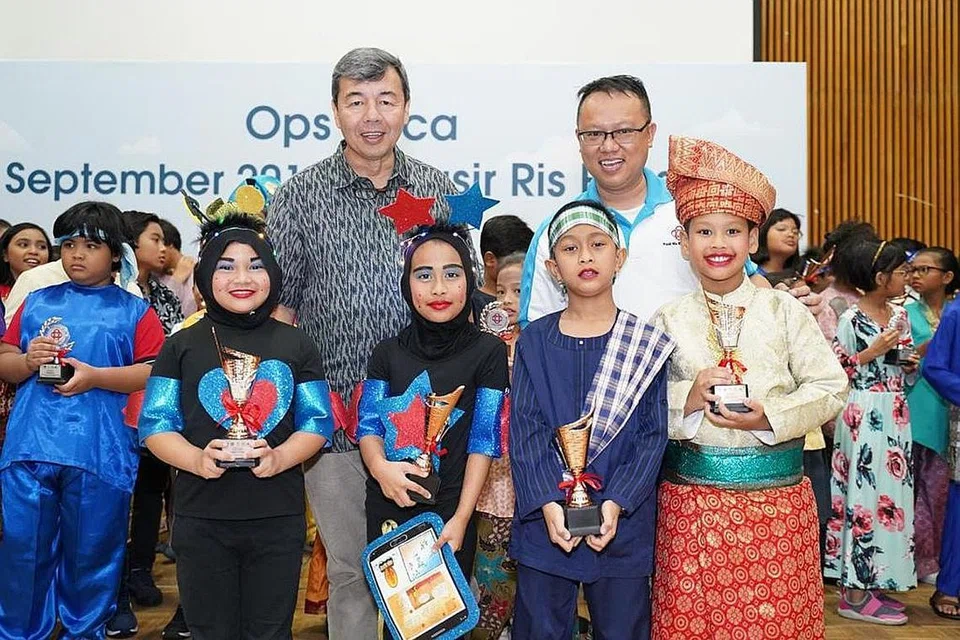 BERSAMA SI CILIK: Encik Syed Ahmad (baju batik) dan Pengerusi MAEC Kelab Masyarakat Pasir Ris Elias, Encik Eirsham Abdul Rashid, bergambar dengan sekumpulan pemenang 'Ops Baca'. - Foto M³@PASIR RIS-PUNGGOL 