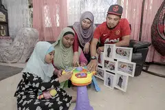 DALAM INGATAN: Encik Mohd Jazlan Hamzah (kanan) dan isteri, Cik Siti Zubaidah Mohd Daud (dua dari kanan) reda dengan pemergian anak bongsu mereka Armel Nadia, yang mengalami Sindrom Down dan meninggal dunia Sabtu lalu kerana kesulitan penyakit paru-paru kronik. Dua anak mereka (dari kiri) Qisya Asmara dan Anggun Farisya turut mengingati keceriaan adik mereka. - Foto BH oleh IQBAL FAIZAL