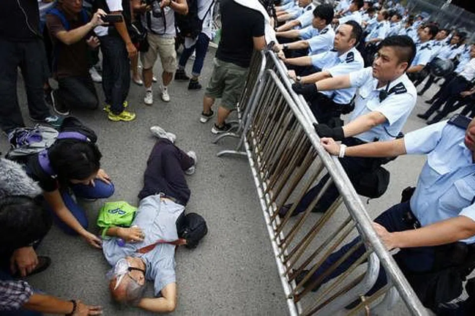 TERUS BANTAH: Polis memerhatikan gelagat seorang penunjuk perasaan yang baring di tempat masuk pejabat Ketua Eksekutif Hongkong, Encik Leung Chun-Ying. Encik Leung mahu membiarkan saja bantahan prodemokrasi berlanjutan sehingga mereka keletihan, namun para penunjuk perasaan bertegas akan tetap membantah selama yang boleh. - Foto REUTERS