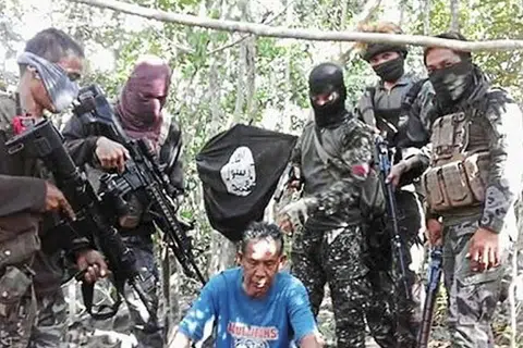 Pengganas Abu Sayyaf bersama salah seorang daripada lima rakyat Malaysia yang diculik mereka di perairan Lahad Datu di pantai timur Sabah pada 18 Julai 2016. Ahmad Tarmizi Muhamad Sayoti disyaki mengajar pengganas kumpulan itu cara membuat bom. 
