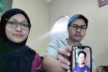 Encik Muhammad Amir Hakimi dan kakaknya, Cik Suraiya Izzaty, menunjukkan gambar bapa mereka, Encik Sabari Baharom, 62 tahun, yang hilang sejak 3 September lalu. 