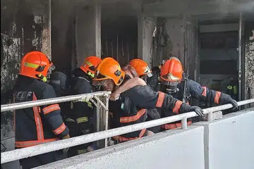 KEBAKARAN MEMBAWA MAUT: Anggota bomba sedang menyelamat seorang penduduk dari unit bersebelahan semalam. - Foto FACEBOOK SCDF, ST ONLINE