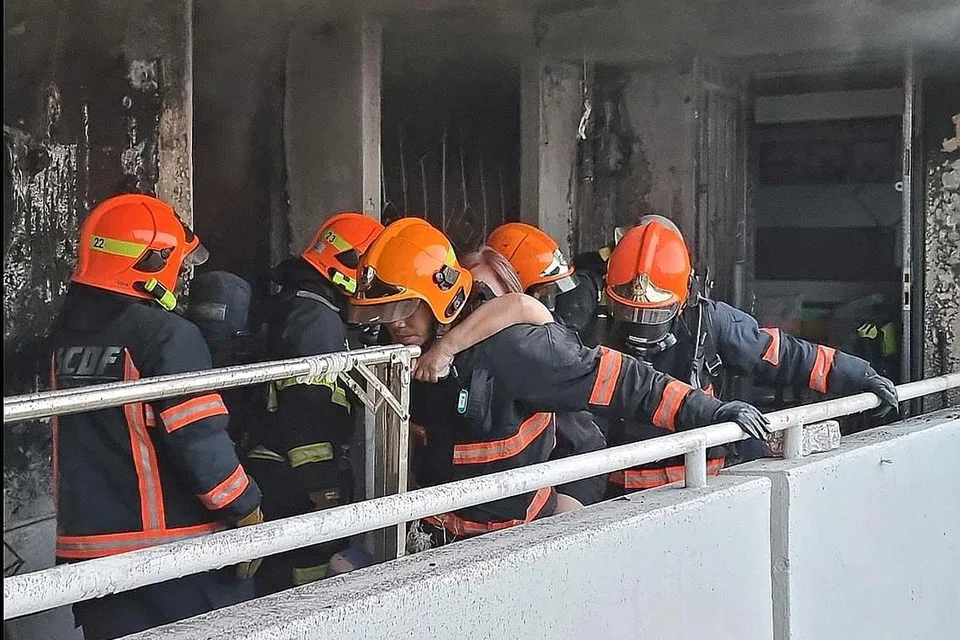 KEBAKARAN MEMBAWA MAUT: Anggota bomba sedang menyelamat seorang penduduk dari unit bersebelahan semalam. - Foto FACEBOOK SCDF, ST ONLINE