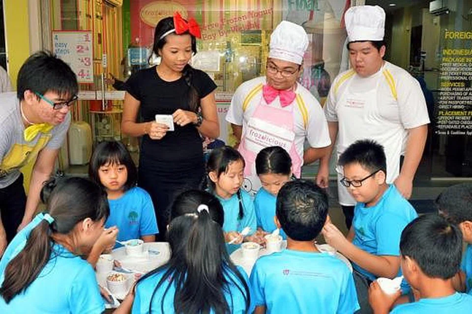 DARI BILIK DARJAH KE DUNIA PERNIAGAAN: Sebagai sebahagian daripada pelan pemasaran mereka, Cik Nurul Ain Afiqah Mohd Shariff (baju hitam) dan kumpulannya daripada ITE Kolej Timur mengedarkan yogurt beku Frozilicious kepada kanak-kanak PCF Tampines di bawah Program Pemasaran Inovasi. - Foto KHALID BABA