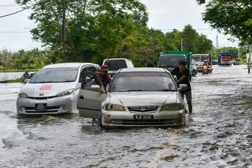 AIR MELIMPAH: Pemandu kenderaan mengharungi air yang melimpah ke jalan raya dekat Kampung Sri Sentosa di Bachok, Kelantan, berikutan banjir kilat susulan hujan lebat.