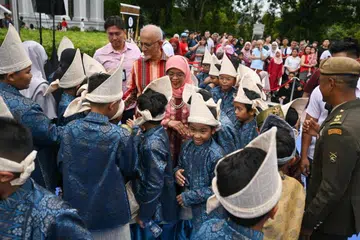 MESRA RAKYAT: Presiden Halimah Yacob dan suaminya, Encik Mohammed Abdullah Alhabshee, bermesra dengan pengunjung dan pelajar di acara Rumah Terbuka di Istana baru-baru ini. 