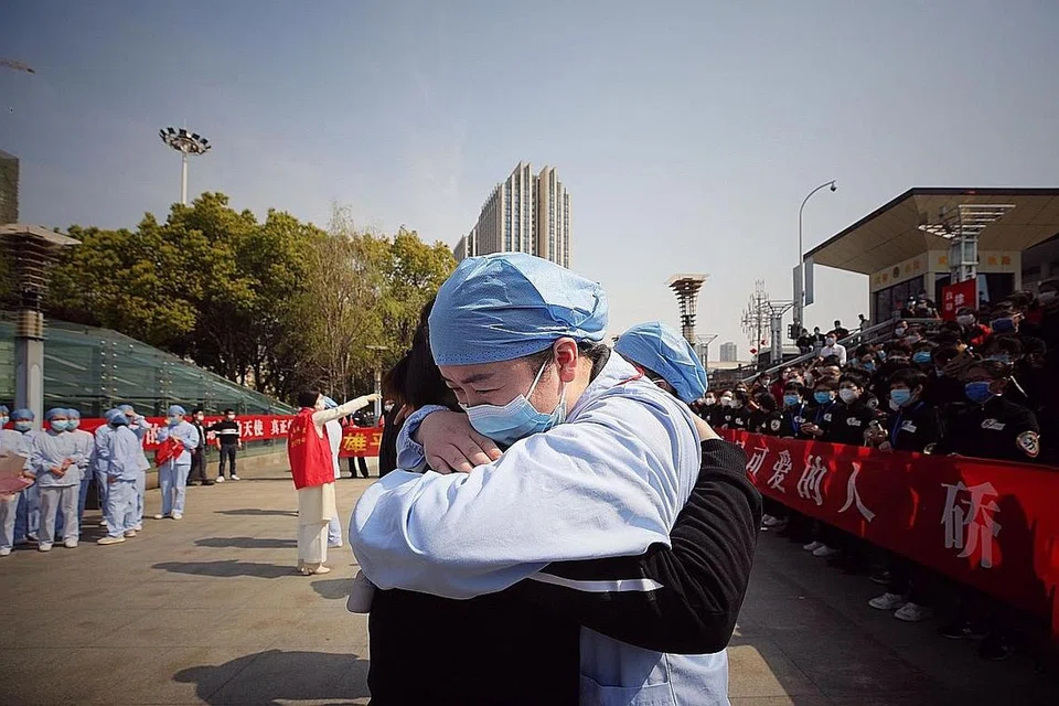 SALING MEMBANTU: Seorang pekerja perubatan dari Wuhan (kanan) memeluk rakan kerjanya yang didatangkan dari wilayah Jiangsu dalam satu upacara menandakan keberangkatan pulang ke wilayah mereka. - Foto AFP