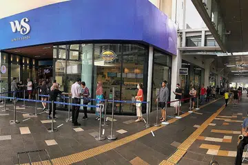 KAWAL JUMLAH PELANGGAN: Orang ramai beratur di luar White Sands di Pasir Ris sedang pusat beli-belah itu mengawal aliran pembeli yang masuk ke tempat itu semalam. - Foto BH oleh KEVIN LIM