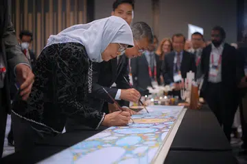 SENTUHAN SENI PAPAR KEPELBAGAIAN: Puan Halimah dan Menteri Kebudayaan, Masyarakat dan Belia, Encik Edwin Tong, memberi sentuhan terakhir pada panel seni yang bertujuan mencetus perbincangan tentang kepelbagaian. Panel itu akan digunakan untuk menghiasi tiang landasan MRT. - Foto BH oleh MARK CHEONG