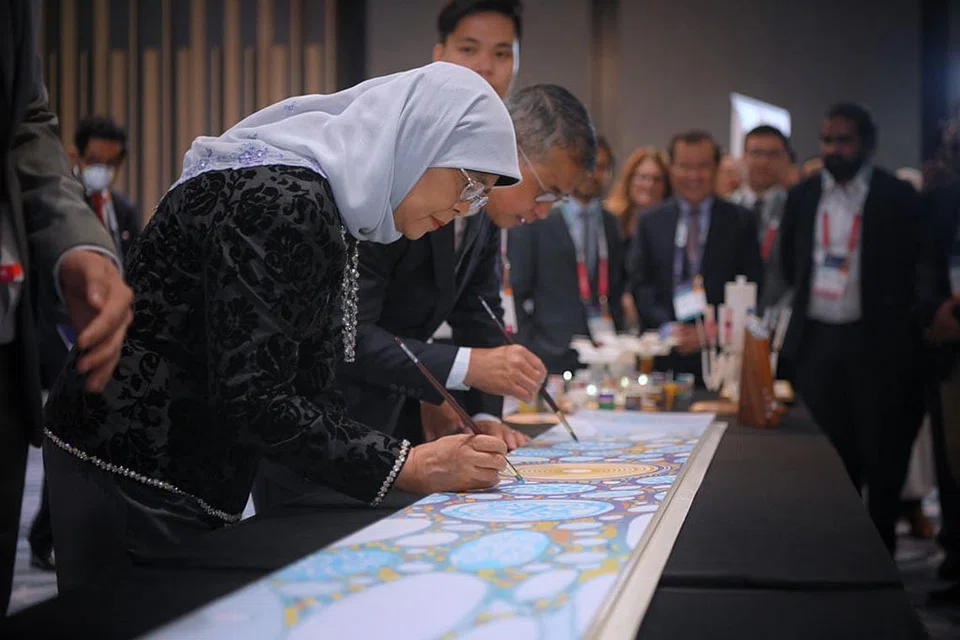 SENTUHAN SENI PAPAR KEPELBAGAIAN: Puan Halimah dan Menteri Kebudayaan, Masyarakat dan Belia, Encik Edwin Tong, memberi sentuhan terakhir pada panel seni yang bertujuan mencetus perbincangan tentang kepelbagaian. Panel itu akan digunakan untuk menghiasi tiang landasan MRT. - Foto BH oleh MARK CHEONG