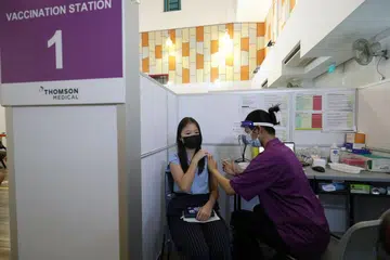 TINDAKAN SELAMAT: Seorang pelajar menerima dos pertama vaksin Covid-19 di pusat vaksinasi di Kelab Masyarakat Bishan semalam. - Foto LIANHE ZAOBAO