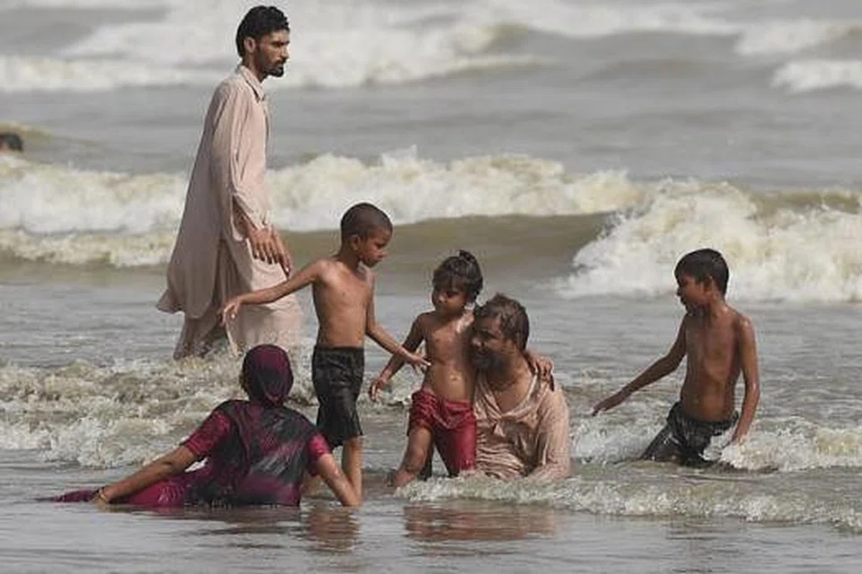 DINGINKAN BADAN: Sekumpulan penduduk Karachi di pantai untuk melarikan diri daripada cuaca panas yang mencengkam Pakistan itu dan telah menyebabkan lebih 600 orang terkorban. - Foto AFP